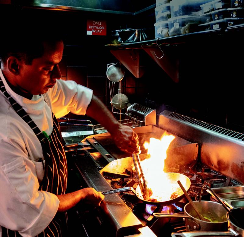 Chef cooking at stove, pan is on fire