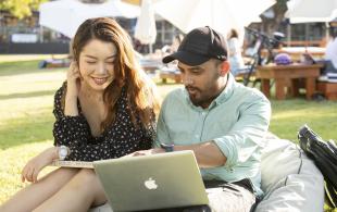 Woman and man viewing laptop screen on the lawn